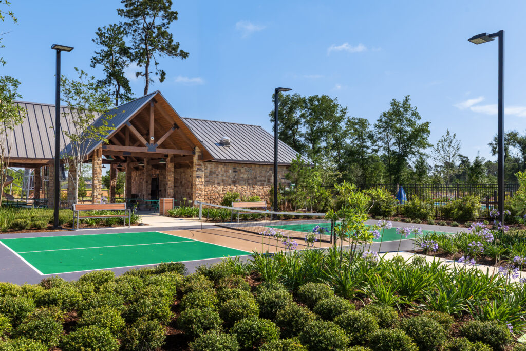 Outdoor pickleball courts adjacent to the community pool pavilion, providing year-round recreational amenities.
